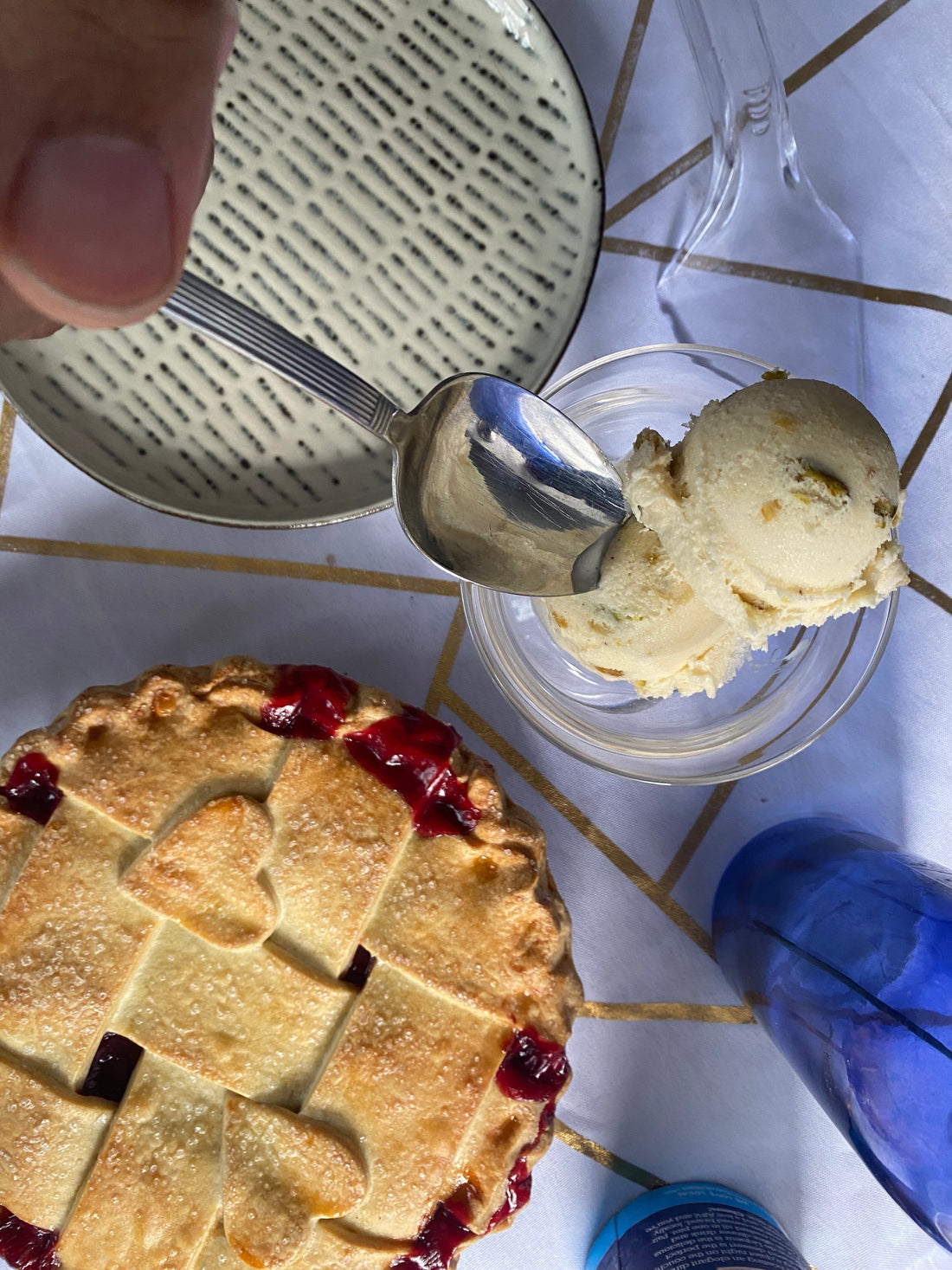 Scoops of ice cream in a glass next to a cherry pie on a table