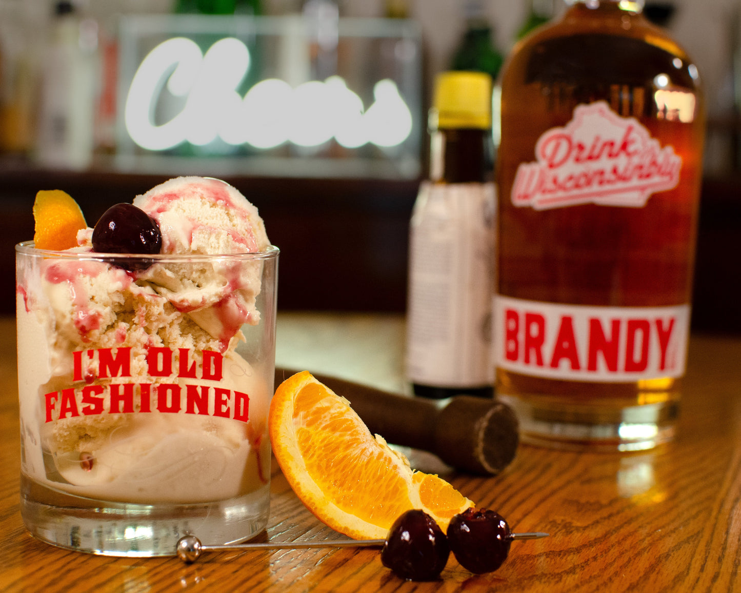 Cocktail glass filled with scoops of Brandy Old Fashioned ice cream with brandy bottle on a wooden surface