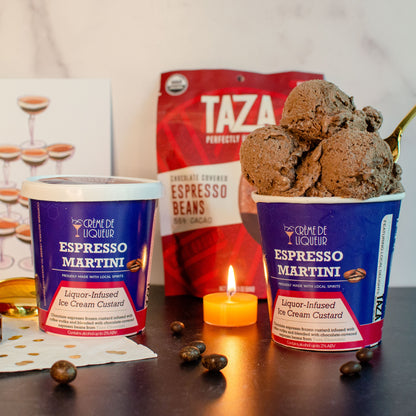Two containers of Espresso Martini ice cream and a bag of Taza chocolate covered coffee beans on a table with a candle, cocktail napkins and spoon