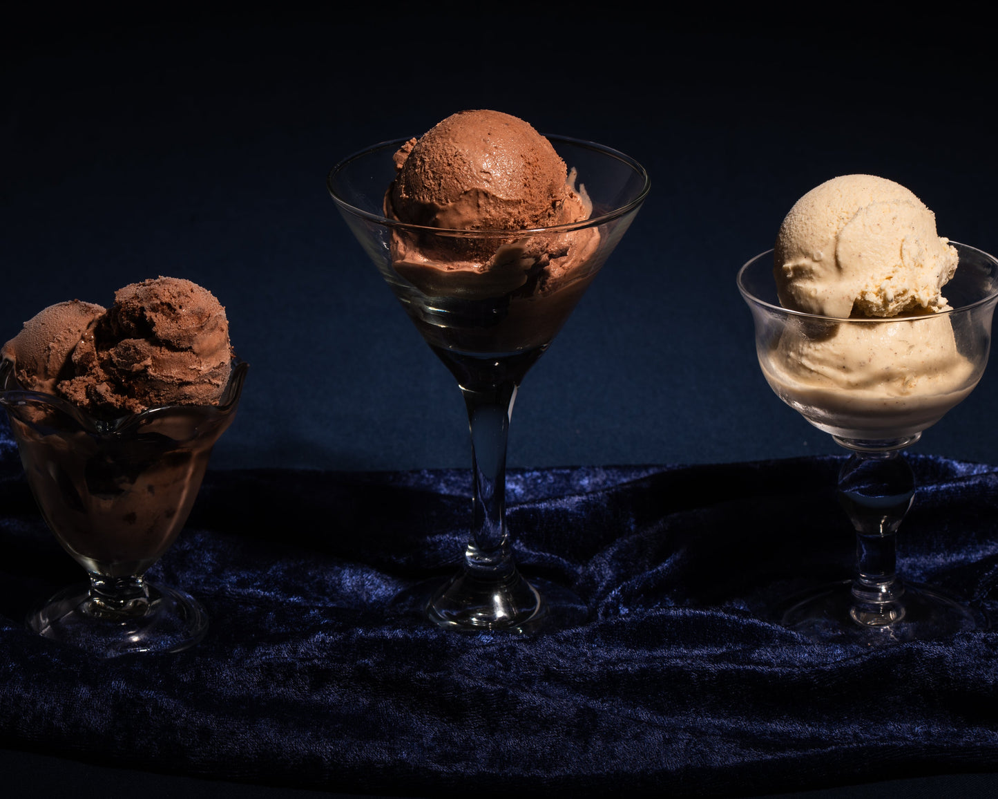 Three glasses with different flavors of boozy ice cream on a dark background