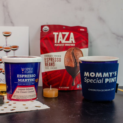 Cup of coffee, Taza coffee beans, and Mommy's Special Pint container on a marble surface.